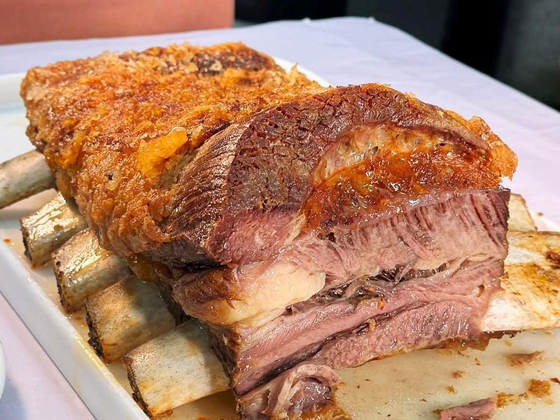 Costela assada e fatiada, com a casca dourada, servida na travessa